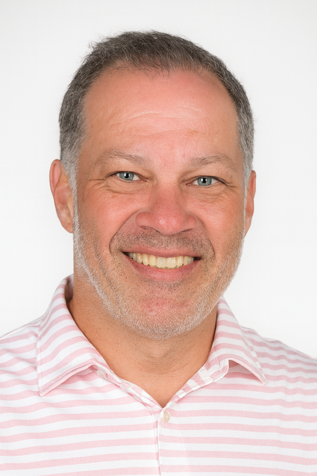 A smiling middle-aged man with short hair and a salt-and-pepper beard, wearing a pink and white striped collared shirt, against a plain white background.