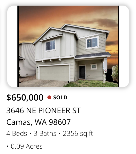 Front view of a two-story house with light-colored exterior siding, a garage, and a covered entrance, under a sunset sky.