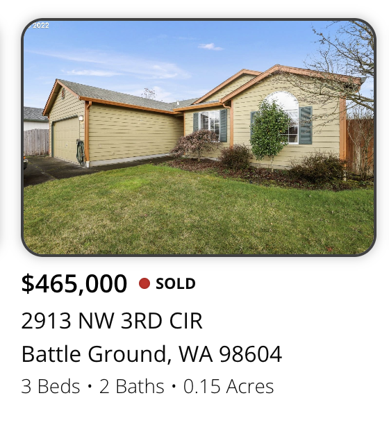 Front view of a beige, single-story house with a gabled roof and a two-car garage, garden area, and blue sky.