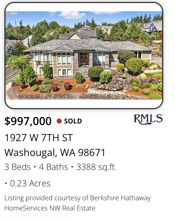 A large, two-story luxury house with a gray roof and stone accents, surrounded by landscaped garden with shrubs, trees, and rocks, marketed and sold by realtor Kelly Craig Graham in Washougal, Washington.