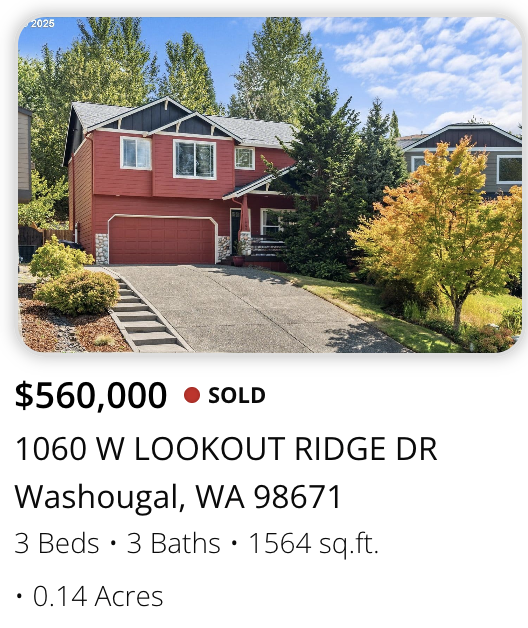 Front view of a two-story red house with a two-car garage, surrounded by trees and a landscaped yard.