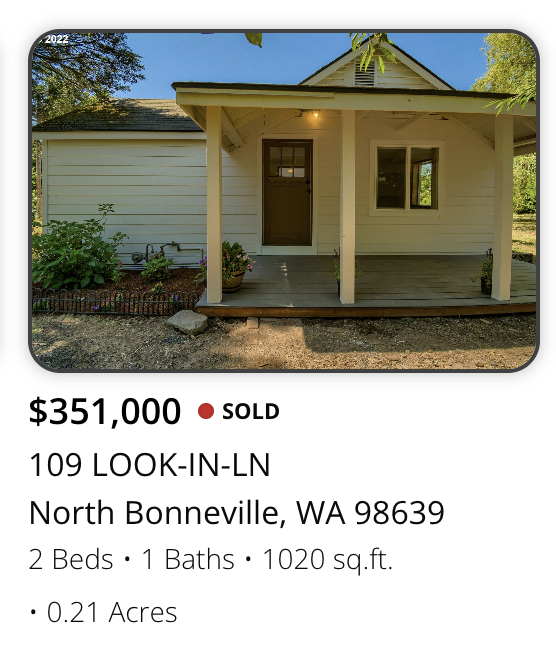 Front view of a small, white, single-story house with a front porch, located in North Bonneville, Washington.