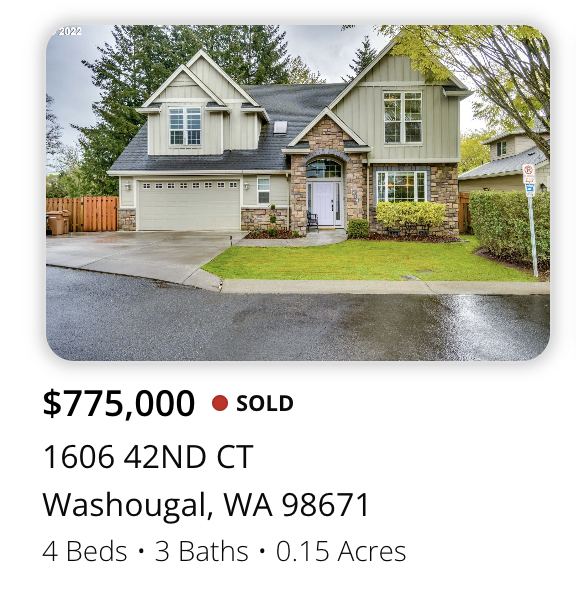 Front view of a two-story house with a garage, landscaped yard, and a sidewalk in front, on a rainy day.