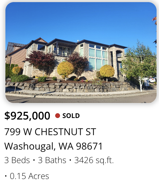 Front view of a modern house on a hill with landscaped yard, trees, and clear blue sky.