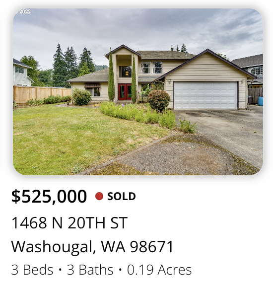 A two-story house with a large front yard and a driveway, located in Washougal, Washington. The house features a red front door, a double garage, and is surrounded by trees and a wooden fence.