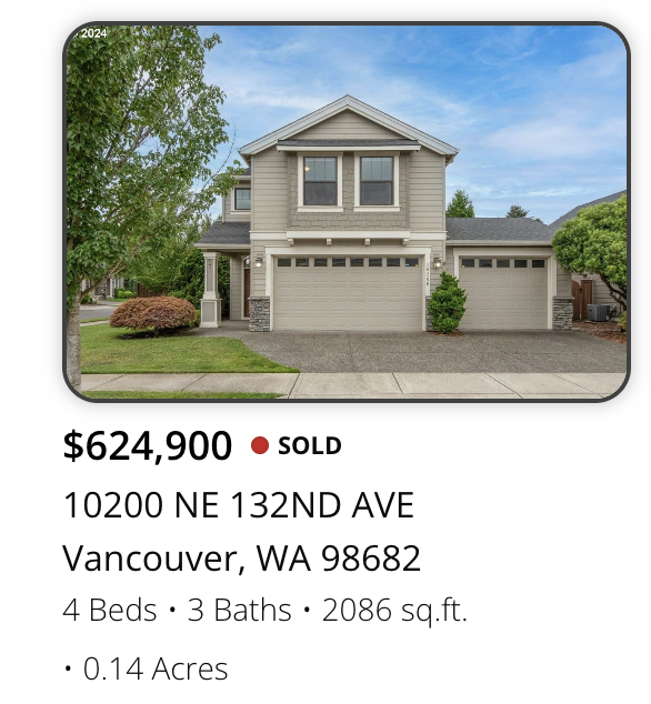 A two-story house with a gray exterior, a three-car garage, and a front lawn with trees and shrubs in Vancouver, Washington.