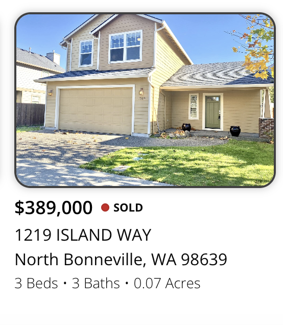 Photo of a two-story house with a beige and yellow exterior, attached garage, green front door, and small front yard with grass and a tree, located on Island Way in North Bonneville, Washington.