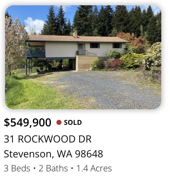 Single-story house with a driveway, surrounded by trees and greenery, located at 31 Rockwood Drive, Stevenson, Washington.