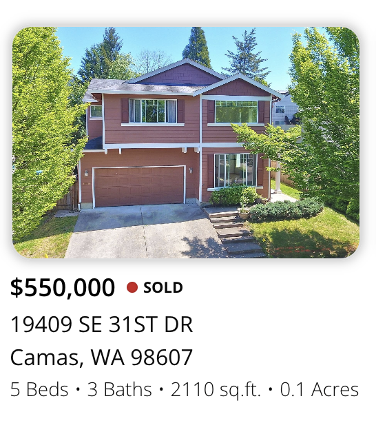 Photo of a two-story house with a red exterior, attached garage, and lush green trees surrounding it.