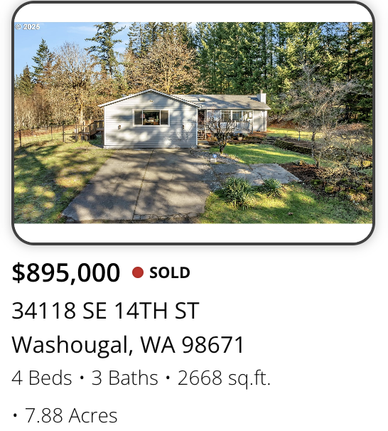 A white house with a deck and large front yard surrounded by trees in Washougal, Washington.
