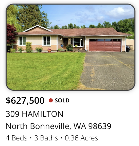 Single-story beige house with a red garage door, front porch, and a well-maintained front lawn, located in North Bonneville, Washington.