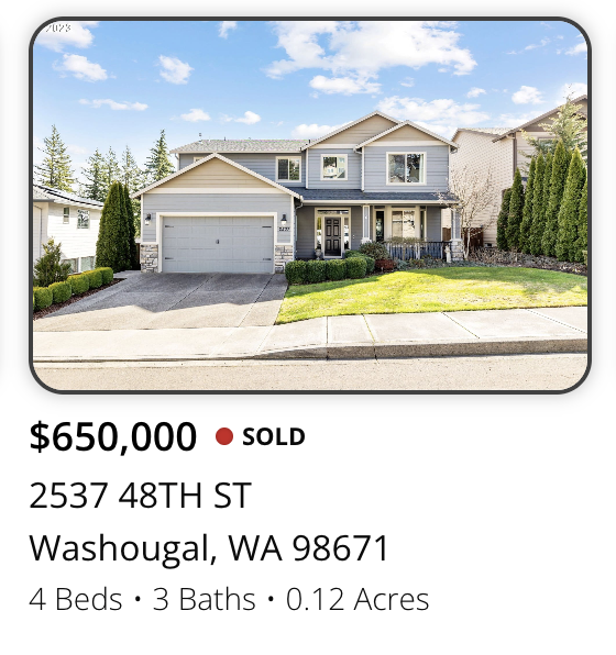 Front view of a two-story house with a garage, surrounded by a lawn and trees, under a blue sky with clouds.