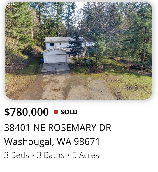 A white two-story house with attached garage surrounded by trees and greenery in a rural setting, with a dirt and paved driveway in the foreground.