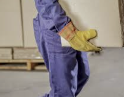 A person in protective clothing holding a trowel, preparing to work on a construction or renovation project.