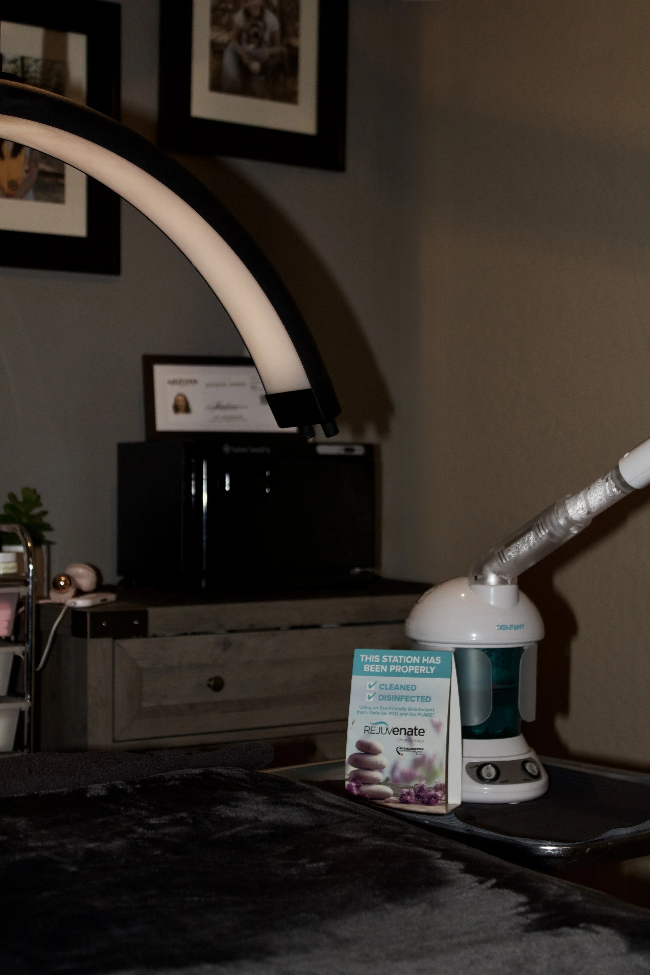 Image of a dental water flosser on a tray next to a sign indicating it has been properly cleaned and disinfected, set on a table in a room with framed pictures and a certificate on the wall.