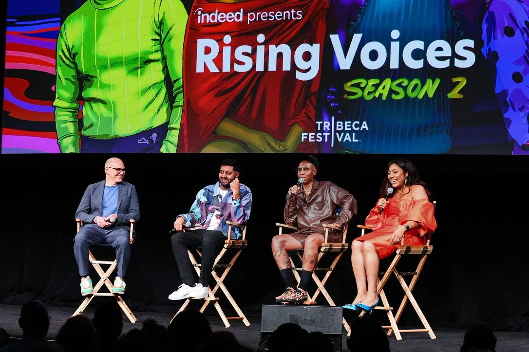 Four people sitting on a stage in director's chairs during a panel discussion at a Rising Voices Season 2 event, with a large colorful screen behind them displaying the event title and branding.