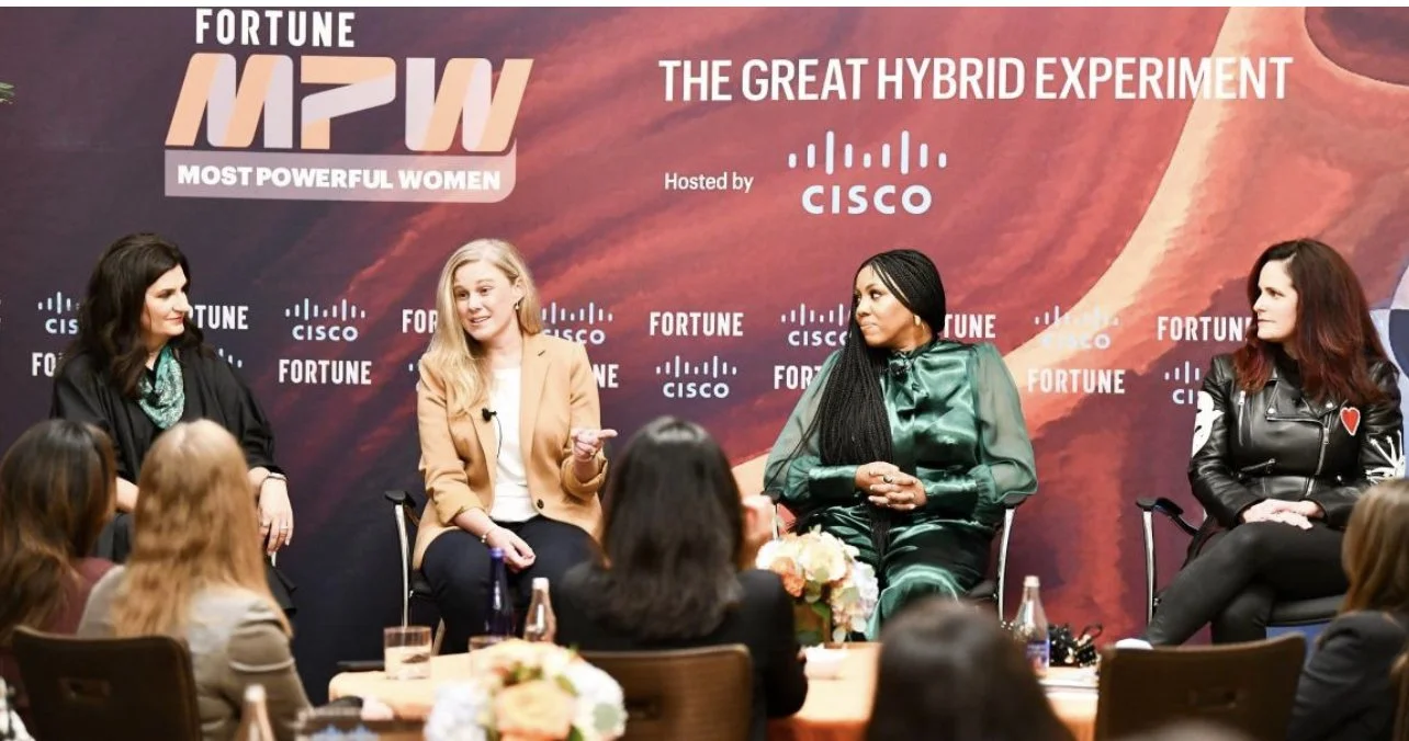 A panel discussion with four women on stage at a 'Most Powerful Women' event, with an audience in front. The backdrop displays 'Fortune MPW', 'The Great Hybrid Experiment', and 'Hosted by Cisco'.