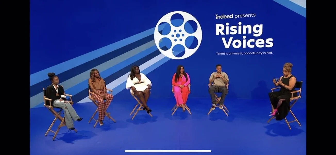 A panel discussion with six diverse individuals seated on stage with a blue background, large logo, and text that reads 'Indeed presents Rising Voices. Talent is universal, opportunity is not.'