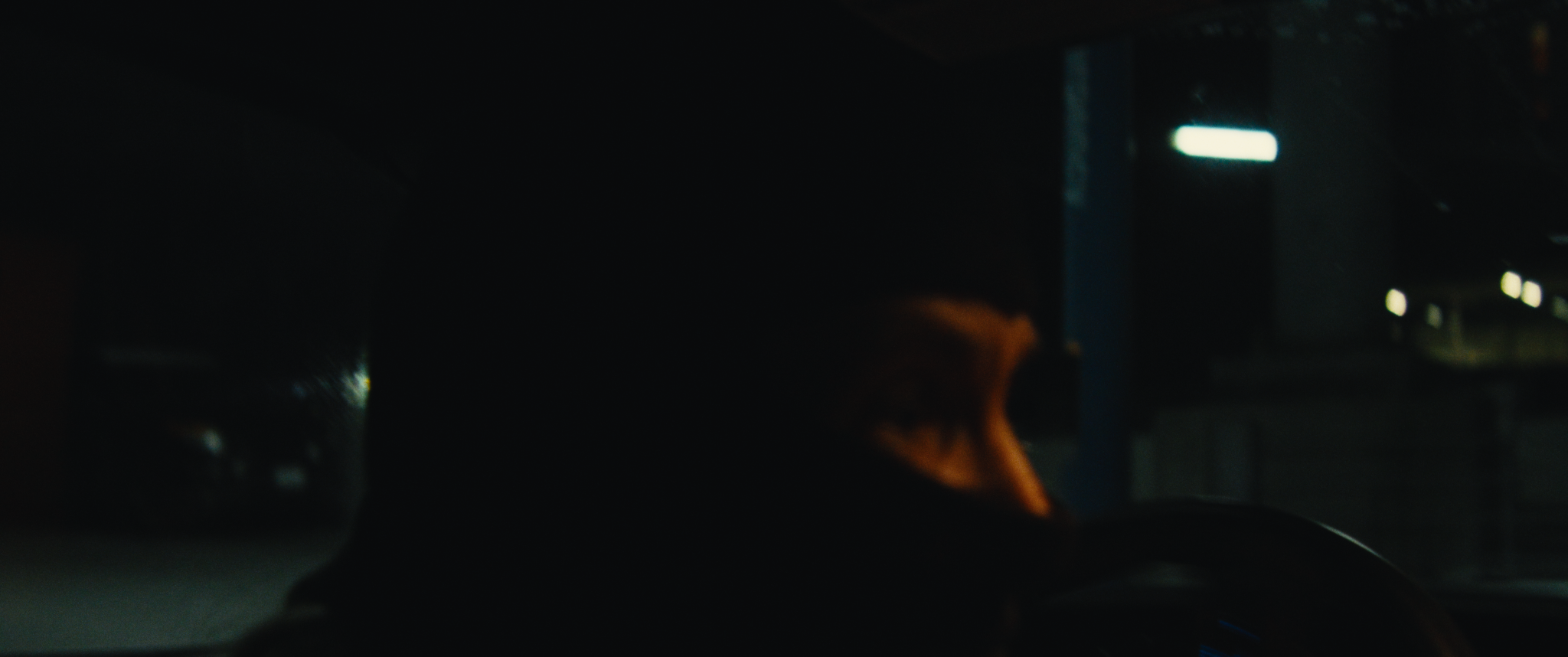 A person with orange hair sitting in a dark car at night.