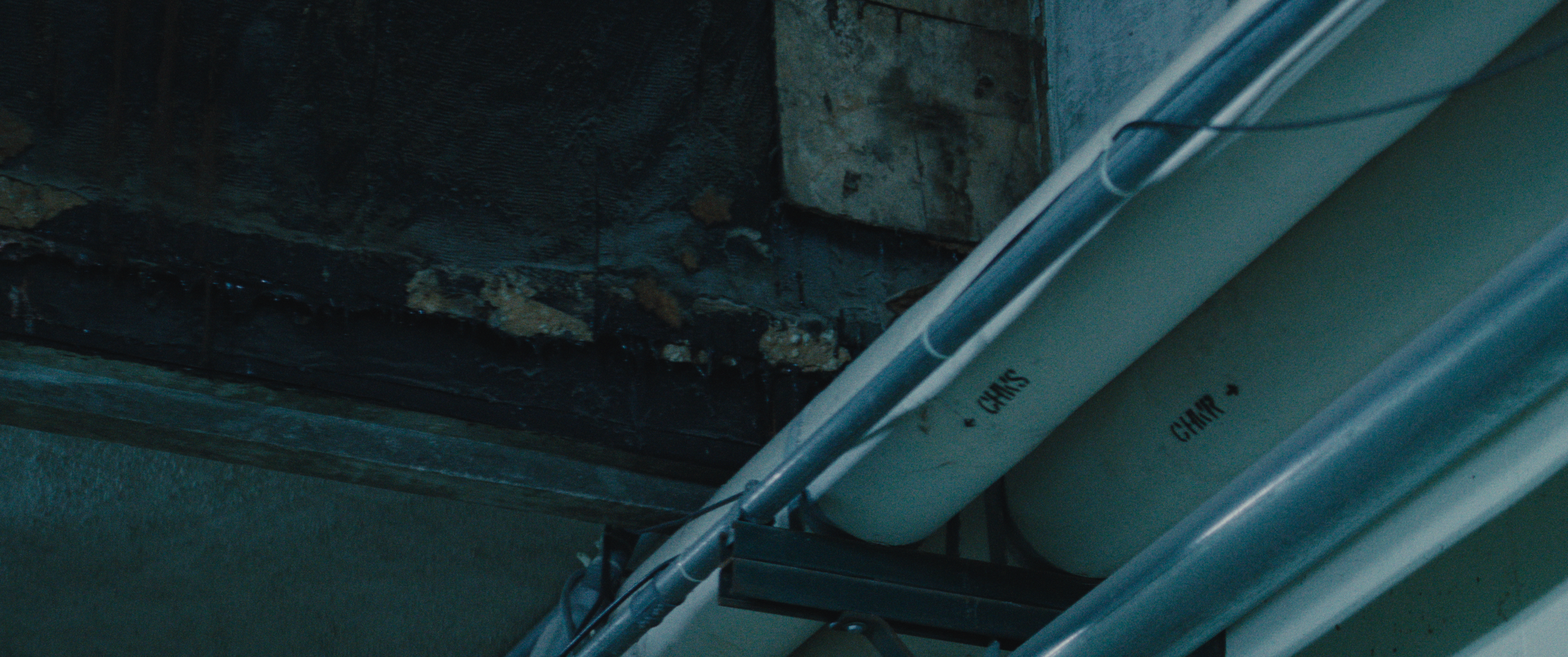 Close-up of a fireplace with soot on bricks and a white PVC pipe labeled 'CHAIS' and 'CHAIR' running nearby.