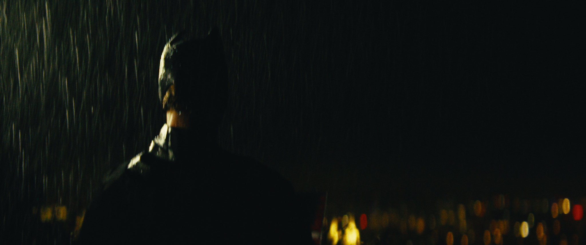 Person walking in the rain at night, with city lights in the background.