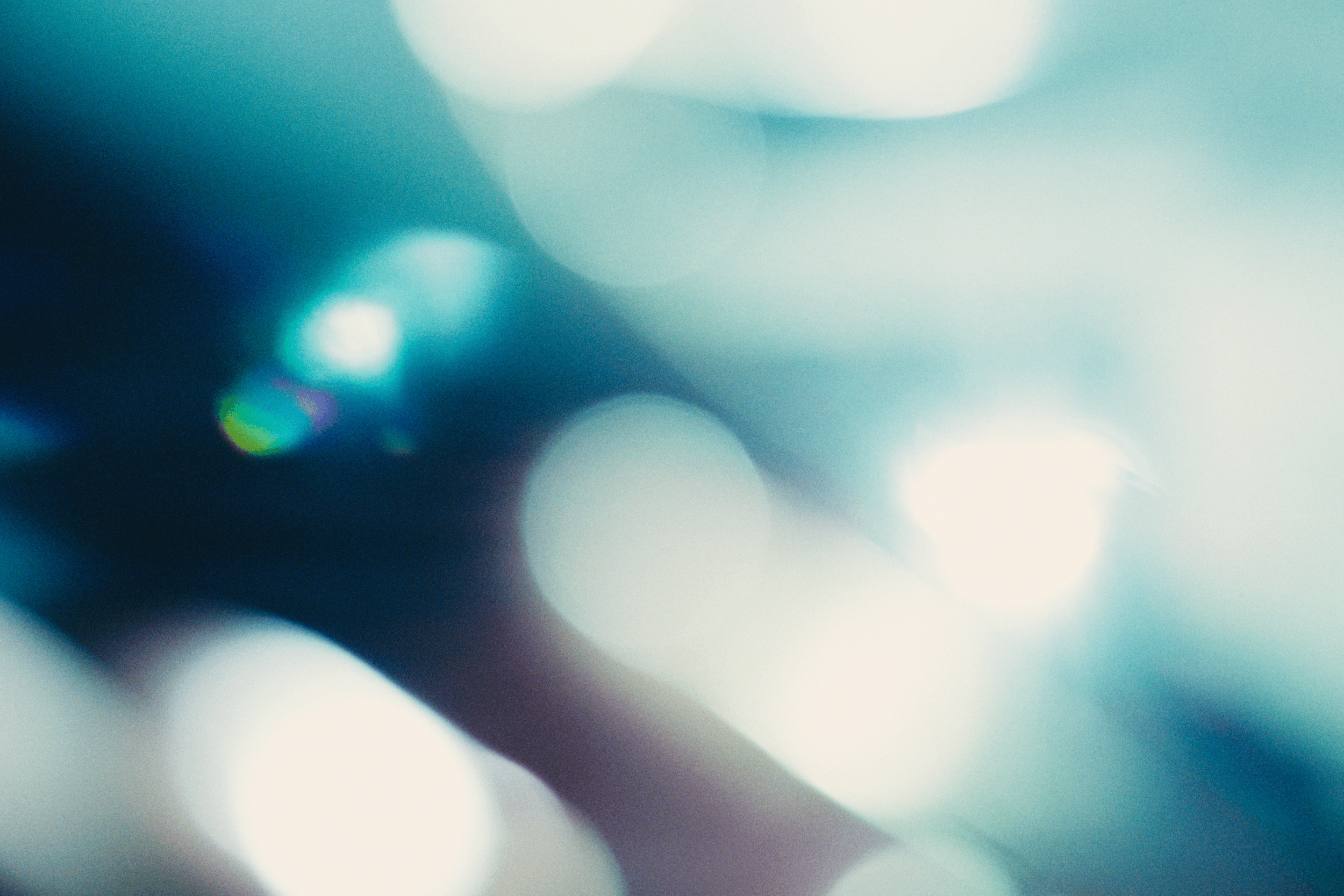 Abstract image with blurry circles of light in various shades of blue, teal, and white, creating a soft, out-of-focus effect.