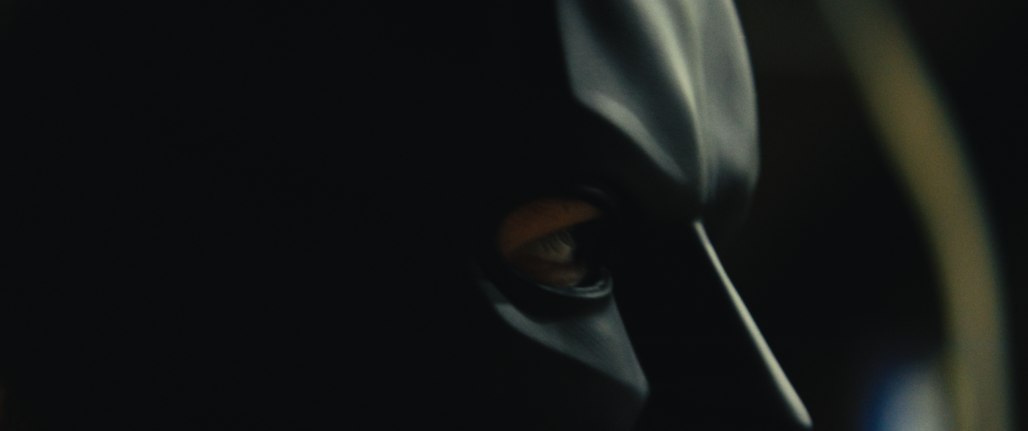 Close-up of a person wearing a cap, looking downward in a dark environment.