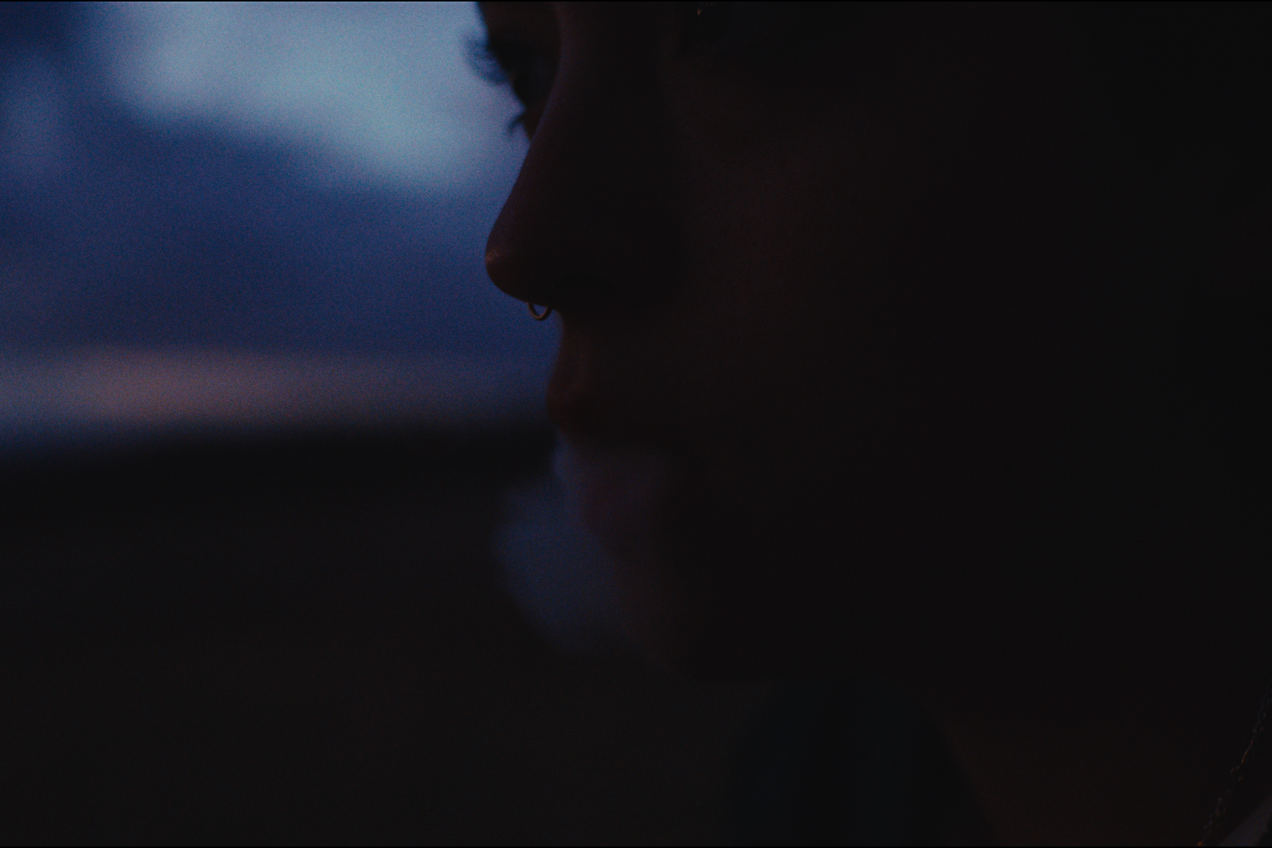 Close-up of a person's face, focusing on the nose and lips, with a dark background and soft lighting.