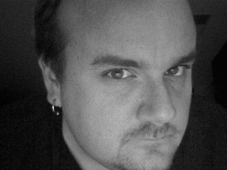 Close-up black and white photograph of a man's face with a partial side profile, short dark hair, and a serious expression.