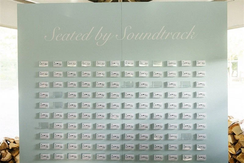 Wall display with multiple cassette tapes arranged in rows under the phrase "Seated by Soundtrack."