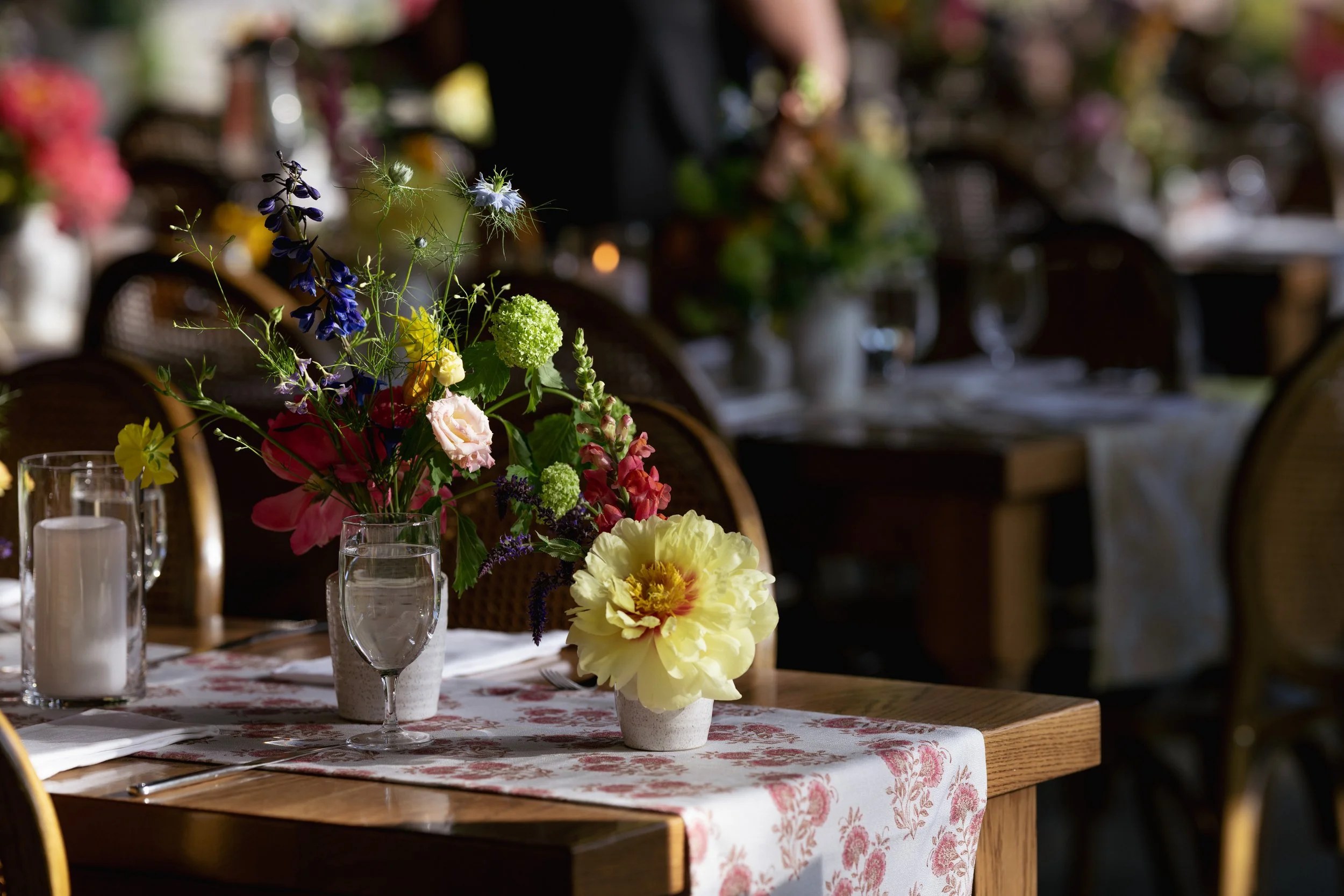 A table decorated with a floral centerpiece, candles, and glassware in a dining setting