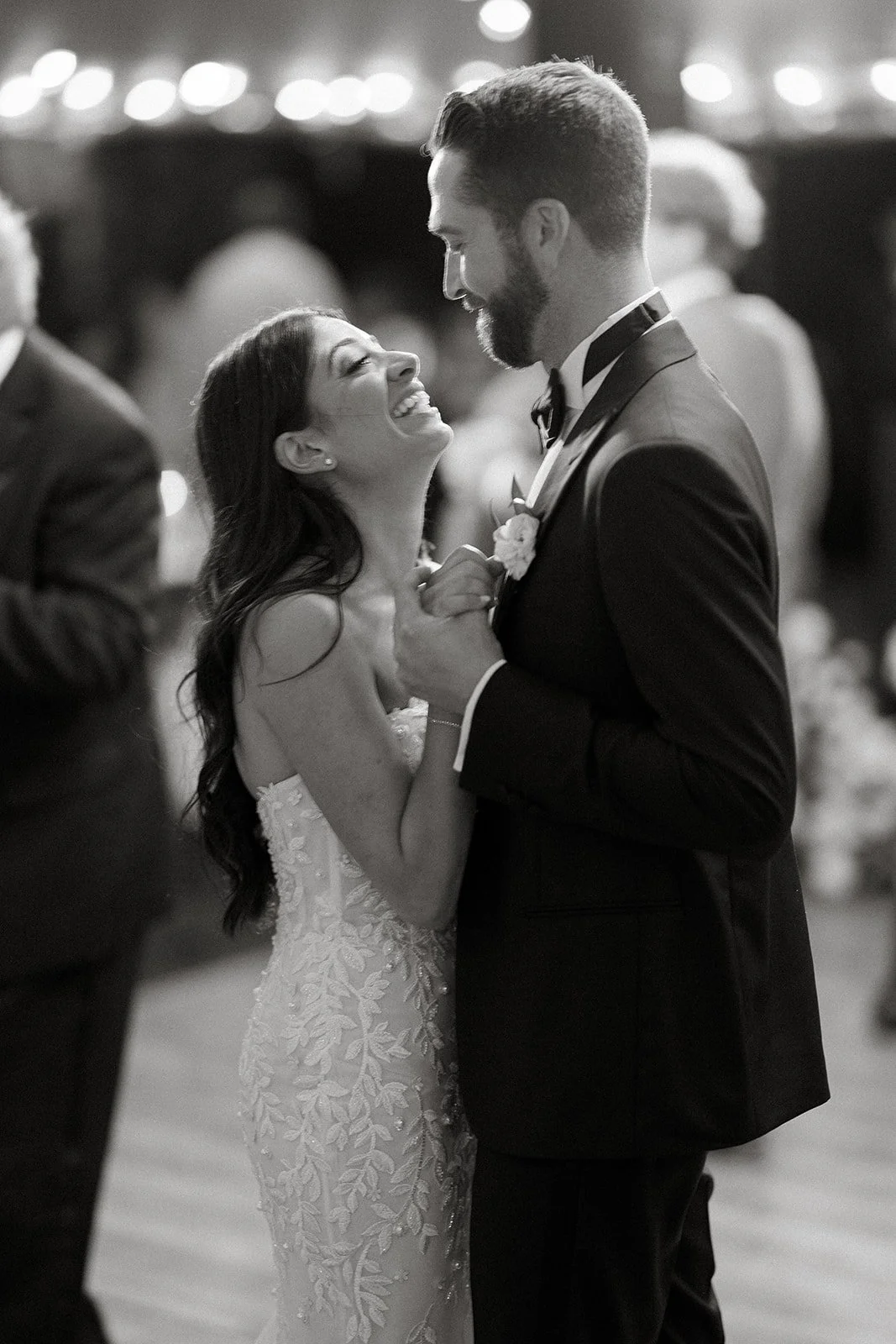 A bride and groom dancing at their wedding reception, smiling and looking into each other's eyes.