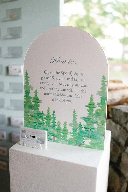 A sign with instructions on how to use Spotify to hear a soundtrack, and a small device on a white pedestal.