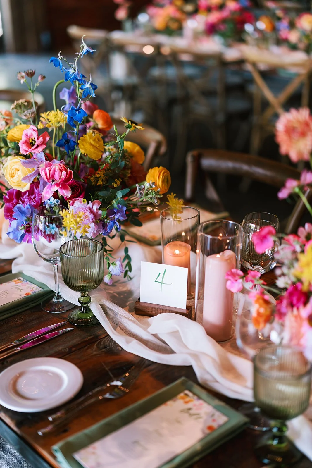 A table set for a celebration with a colorful flower arrangement, candles, glassware, and tableware. The table number is 4.