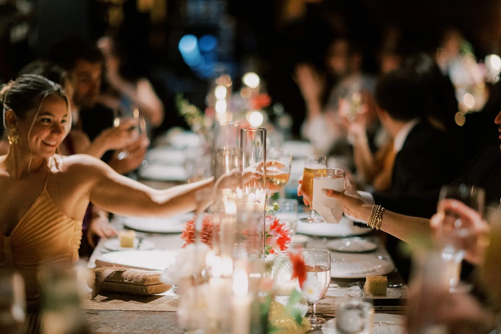 People gathered at a dinner table raising glasses in toast at an elegant celebration.