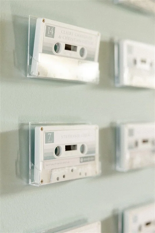 Cassette tapes in clear plastic cases mounted on a light green wall.