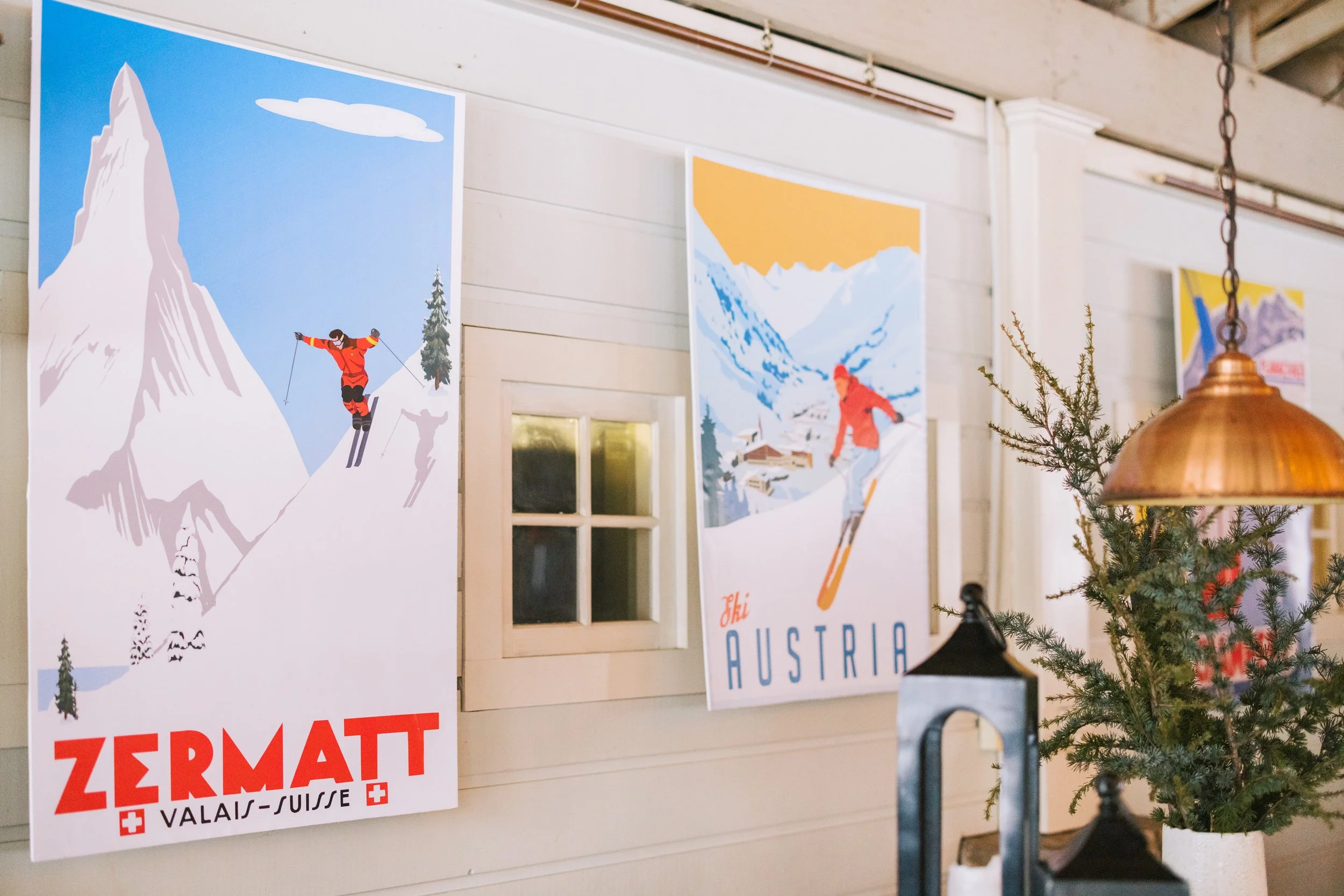Decorative posters of winter ski scenes and a small Christmas tree on a wall.