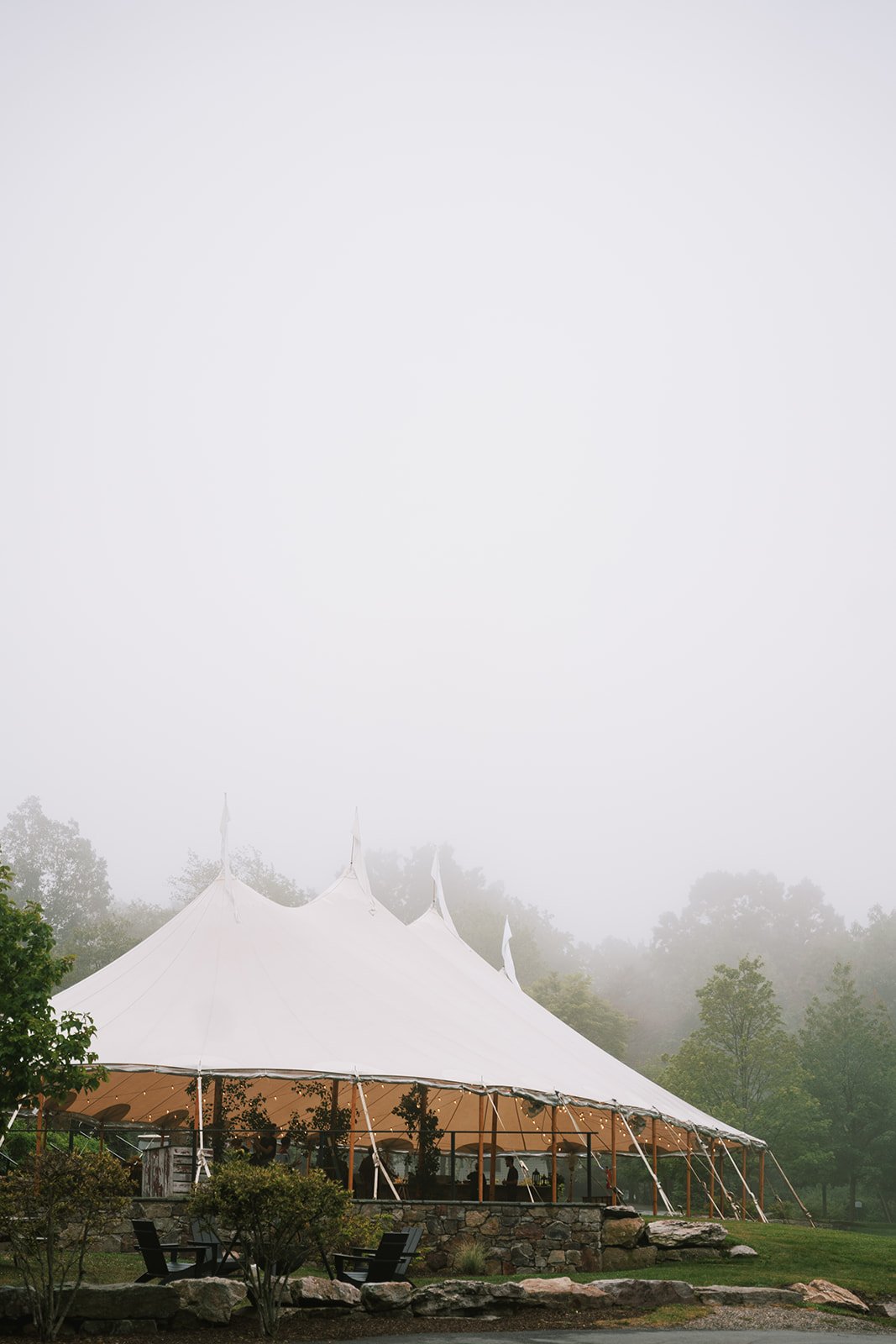 Large white event tent in a foggy outdoor setting with trees in the background and seating arrangement in the foreground.