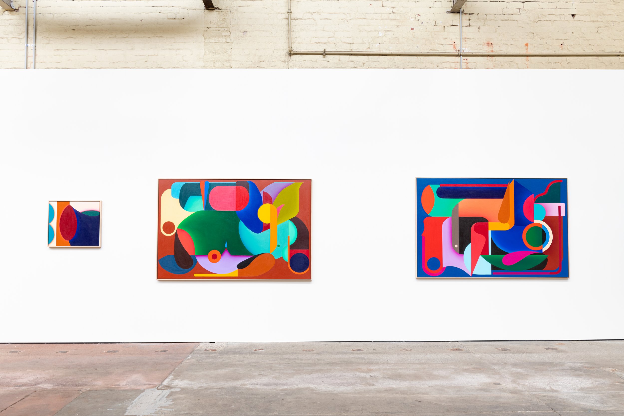 Three colorful abstract paintings displayed on a white gallery wall in an art exhibition.