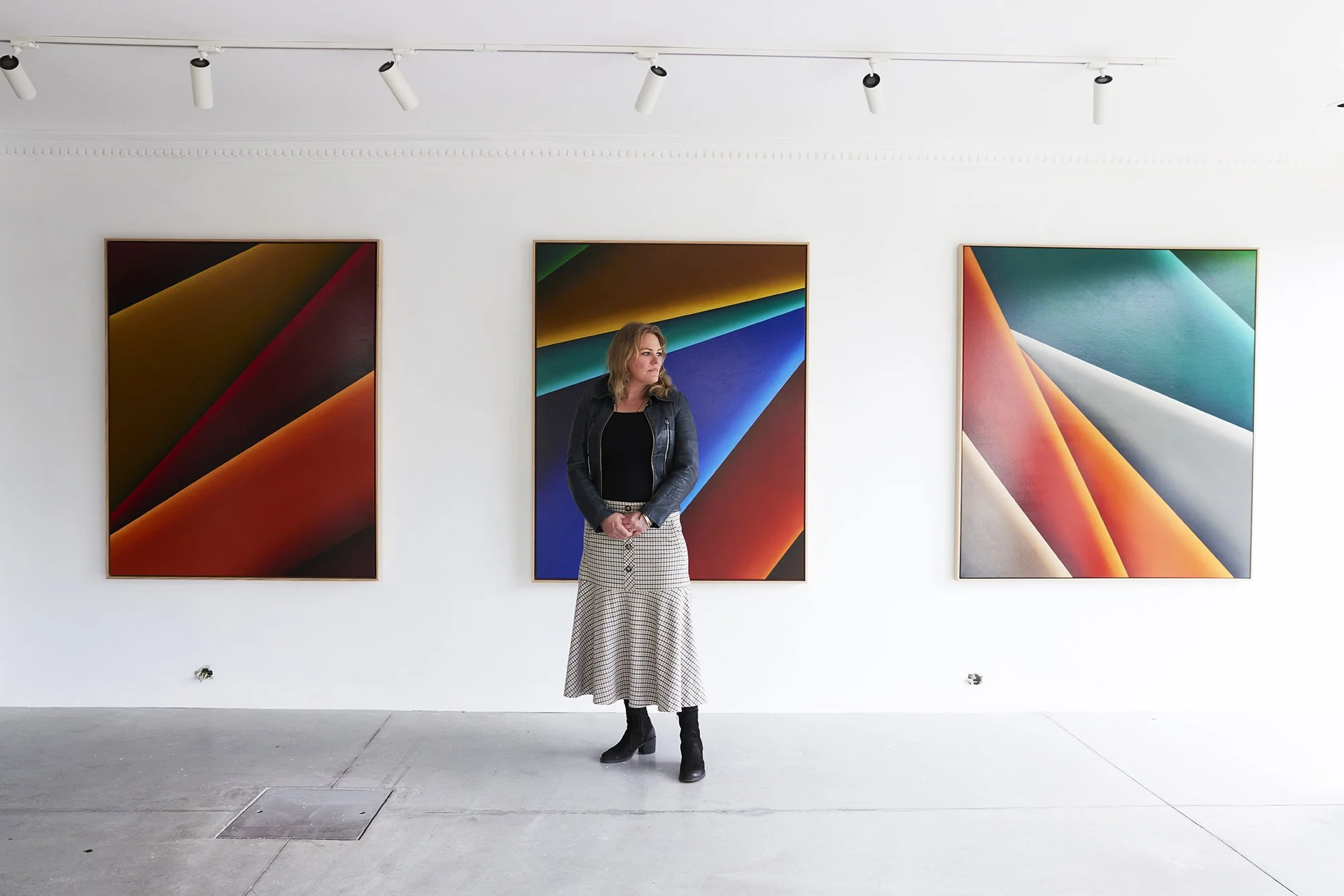 Beth Gibbeson contemporary Australian painter standing with her abstract landscape paintings in a gallery exhibition Surface to Air at Saint Cloche Gallery