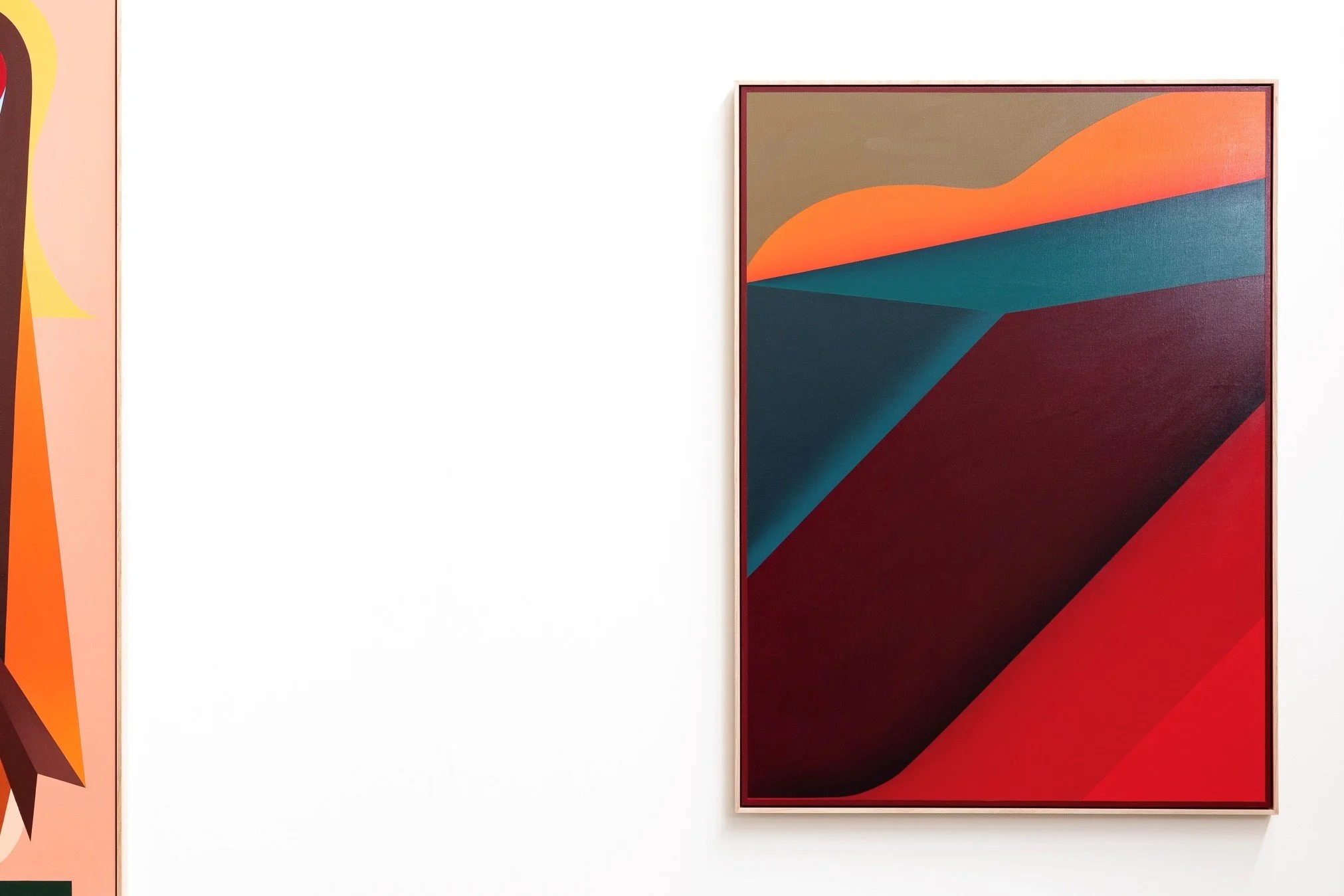 Abstract geometric artwork with bold colors on a canvas, including shades of orange, teal, dark blue, and red, framed and mounted on a white wall.