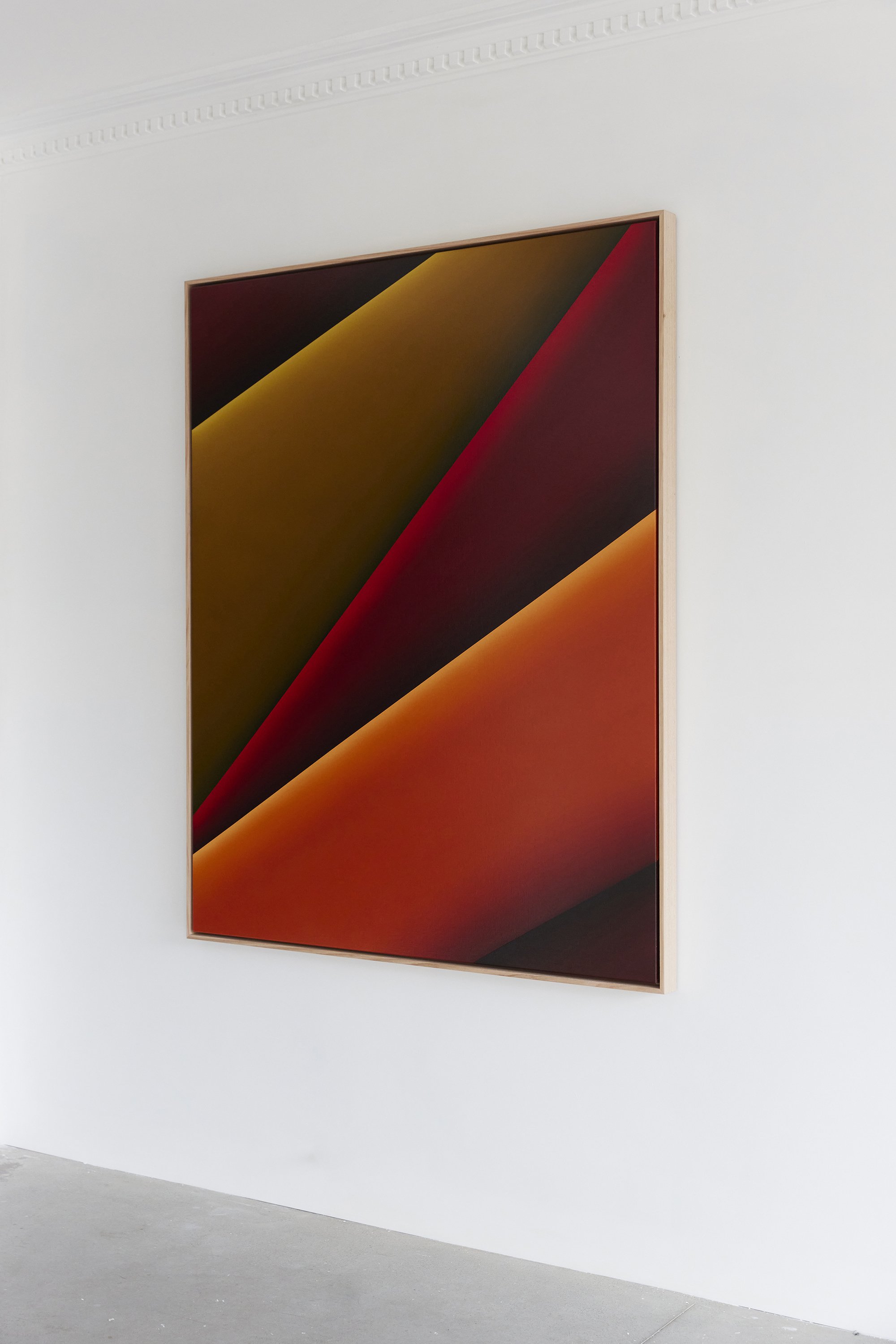 Abstract geometric artwork with bold diagonal colors including yellow, red, orange, and black displayed on a white gallery wall.