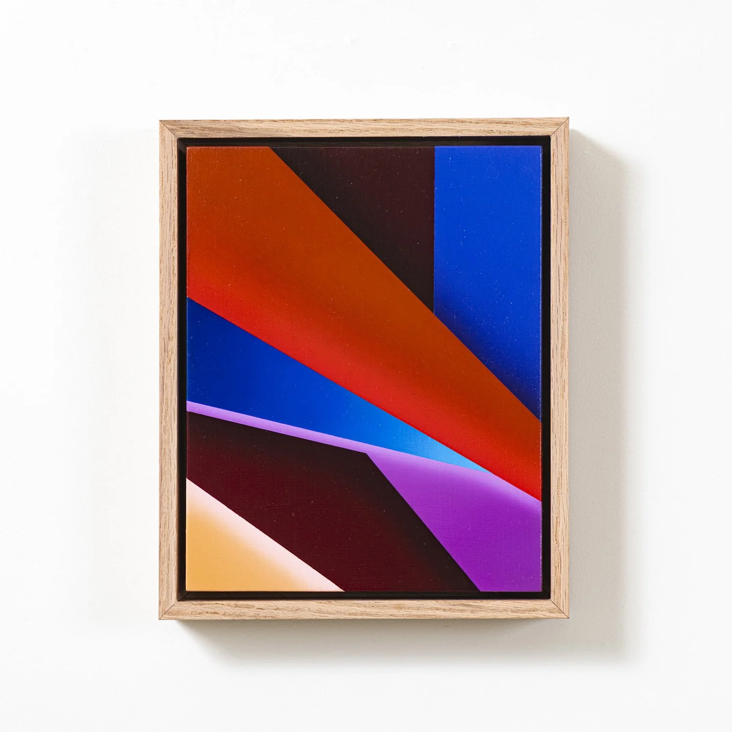Abstract colorful geometric art with red, black, blue, purple, and beige shapes framed in light wooden frame.
