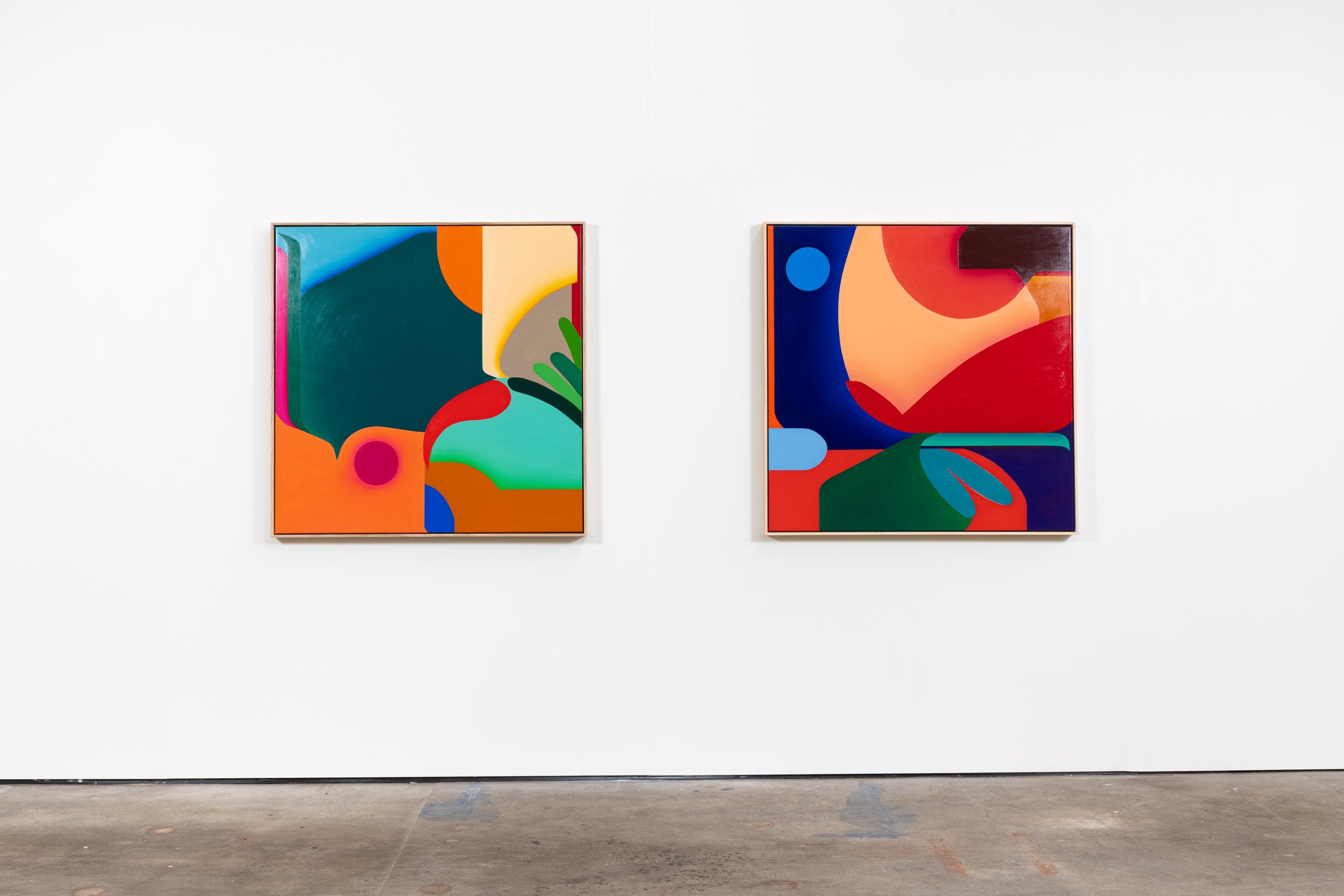 Two colorful abstract paintings hang on a white gallery wall, side by side.