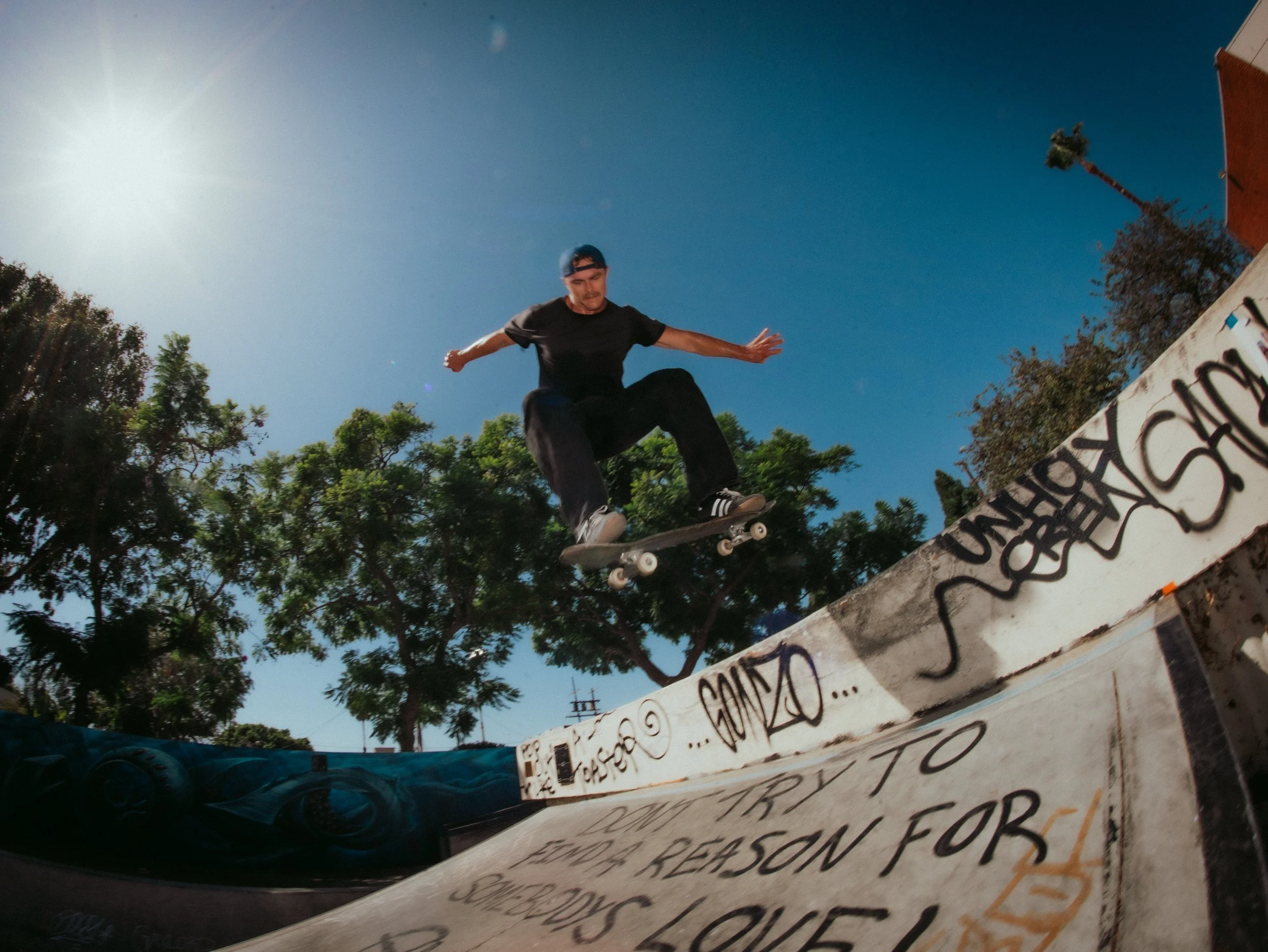 Isaiah Rojers ollies over a graffiti ramp at the West LA Courthouse skatepark, Los Angeles skate photography by Osy Ikhile