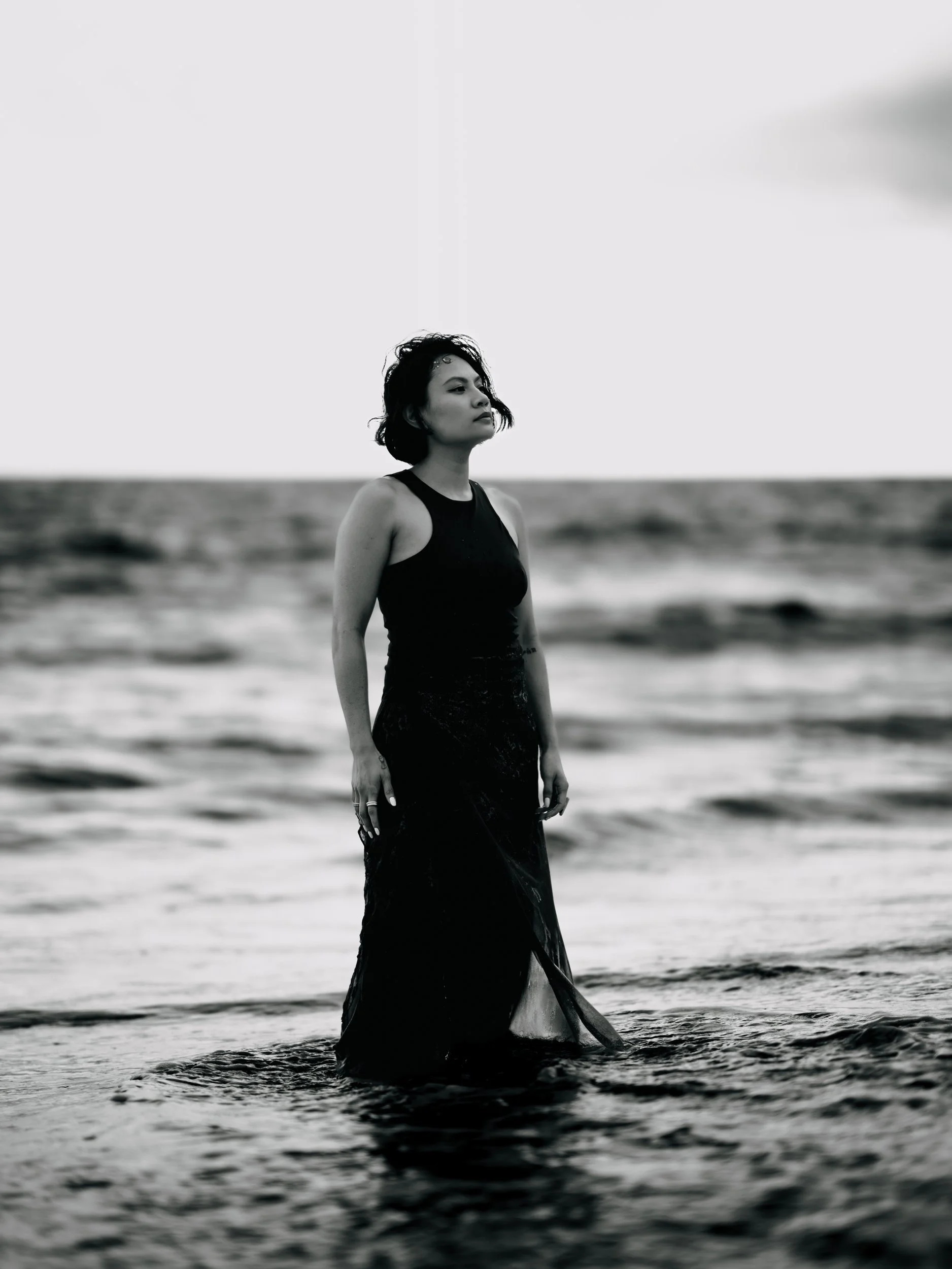 Shaina Rae standing in the sea in a black dress, black and white