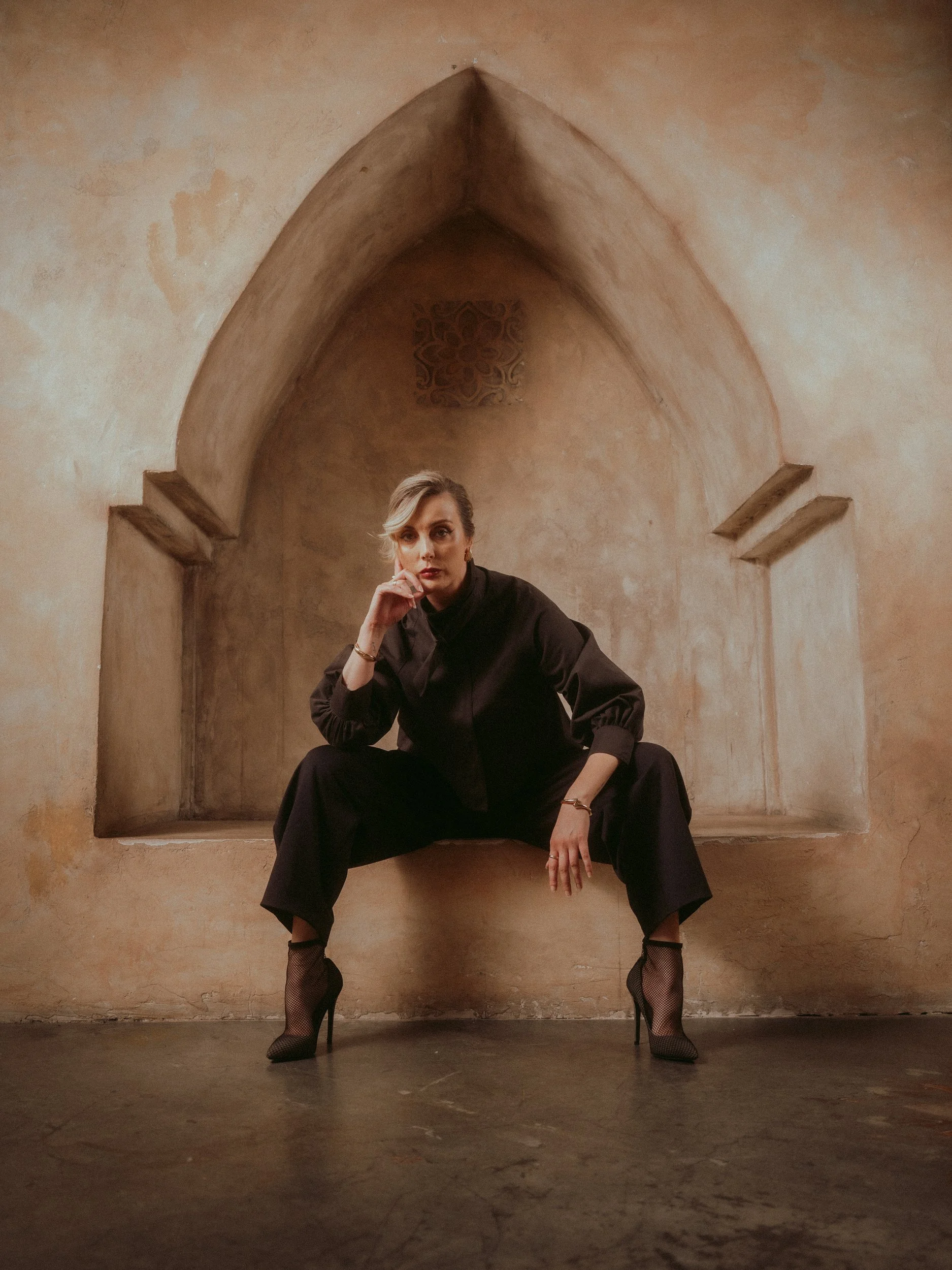 Milanka Brooks seated in a keyhole nook in black tailoring, editorial fashion photography by Osy Ikhile, Los Angeles