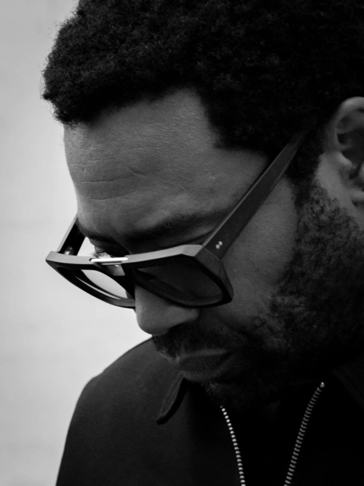 Man looking down in bold Kirk & Kirk sunglasses, black and white
