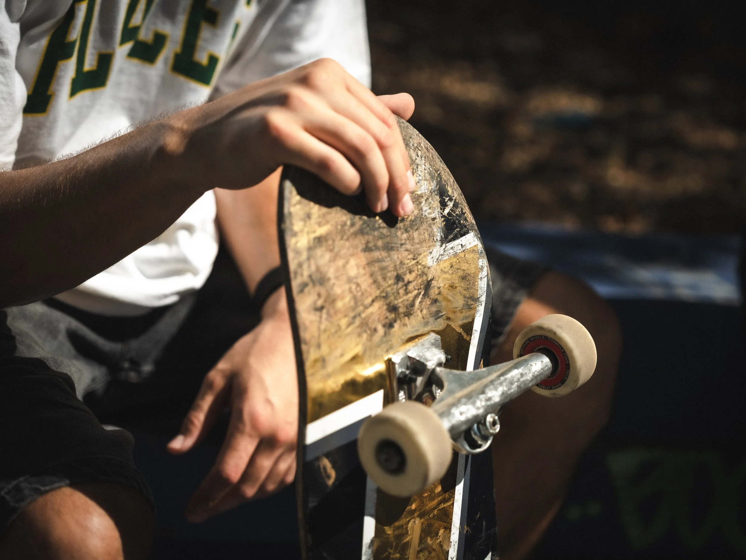 Close-up of hands on a worn skateboard deck at the West LA Courthouse skatepark, Los Angeles skate photography by Osy Ikhile