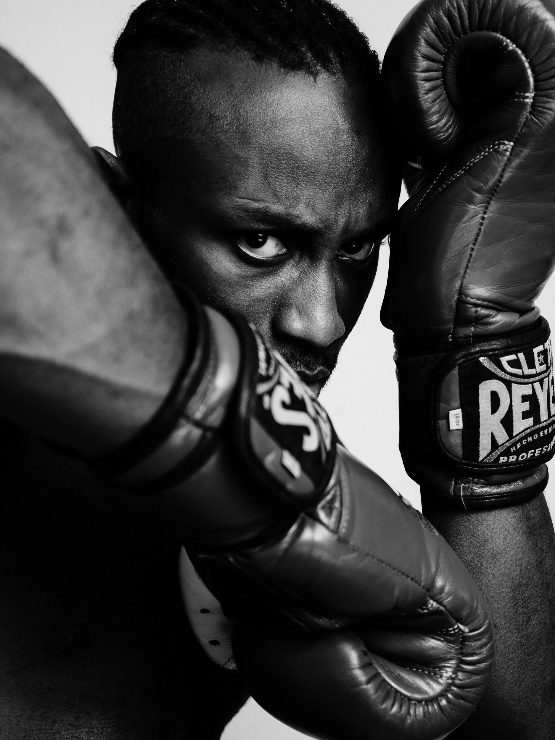 Paul Bossman behind Cleto Reyes boxing gloves, black and white fight portrait